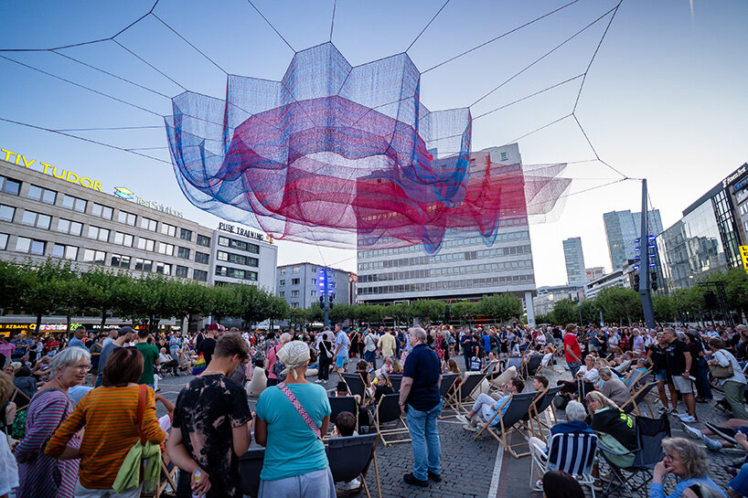 Janet Echelman suspends 103 kilometers of fiber over a Frankfurt plaza, lit by 24 fixtures mounted on its own support pylons